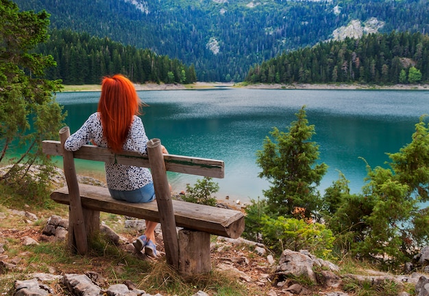 Femme est assise sur un banc et regarde sur le lac