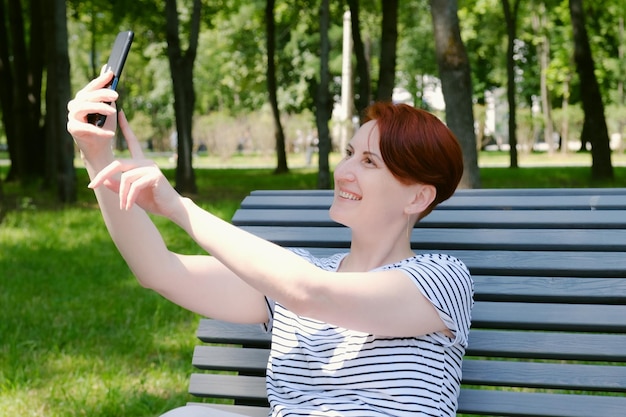 Une femme est assise sur un banc et utilise un téléphone portable.