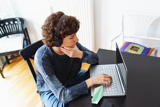 Une femme est assise à un bureau avec un ordinateur portable et un livre sur la table.