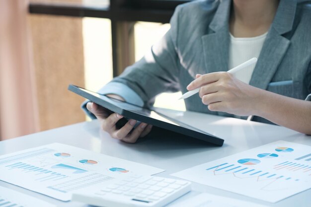 Une femme est assise à un bureau avec une tablette et un stylo