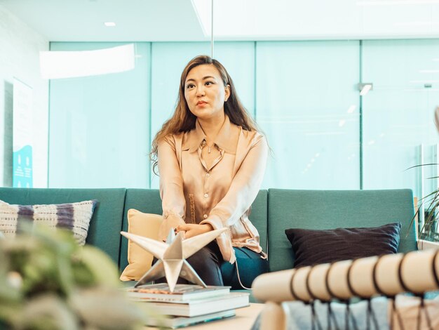 une femme est assise sur un canapé avec un livre à la main