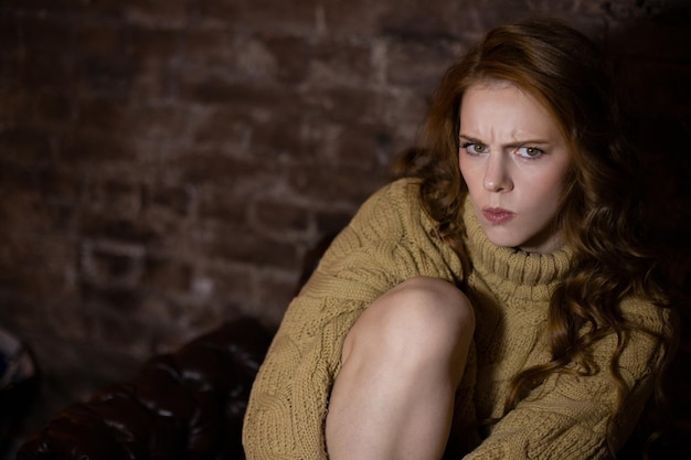 Une femme est assise sur un canapé avec un regard sale sur son visage.