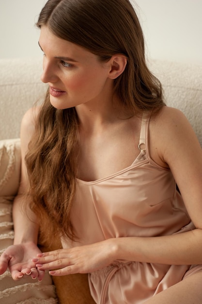 Une femme est assise sur un canapé et regarde une tablette.