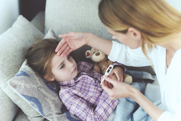 Une femme est assise à côté d'une petite fille malade.