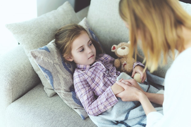 Une femme est assise à côté d&#39;une petite fille qui est malade