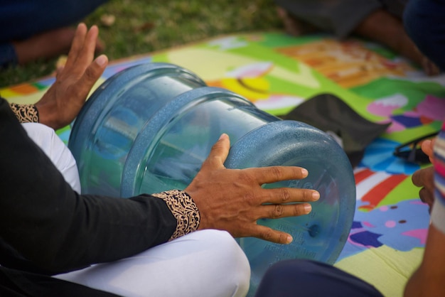 Une femme est assise sur une couverture avec une bouteille bleue à la main.