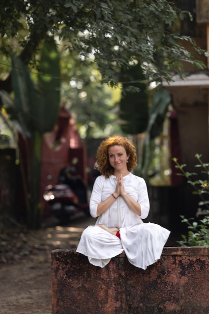 Une femme est assise dans un arbre dans une pose de yoga.