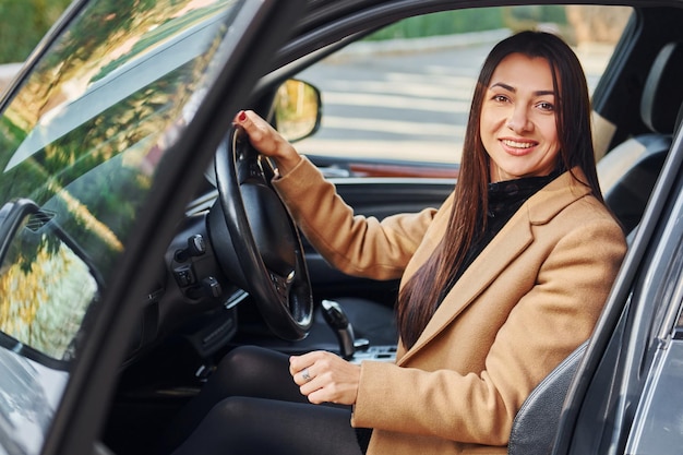 La femme est assise dans une automobile moderne de couleur noire