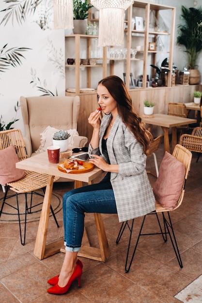 Une femme est assise dans un café et mange des fraises.Une fille avec des fraises dans ses mains dans un café.