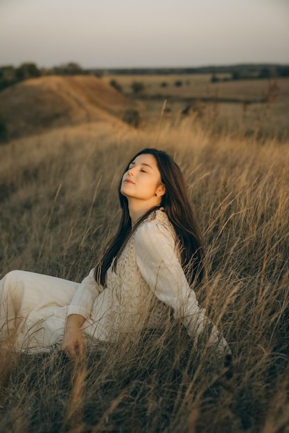 une femme est assise dans un champ avec le soleil brillant sur son visage