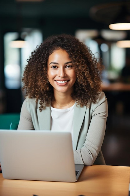 une femme est assise devant un ordinateur portable avec un sourire sur le visage