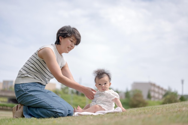 Une femme est assise sur l'herbe avec son bébé