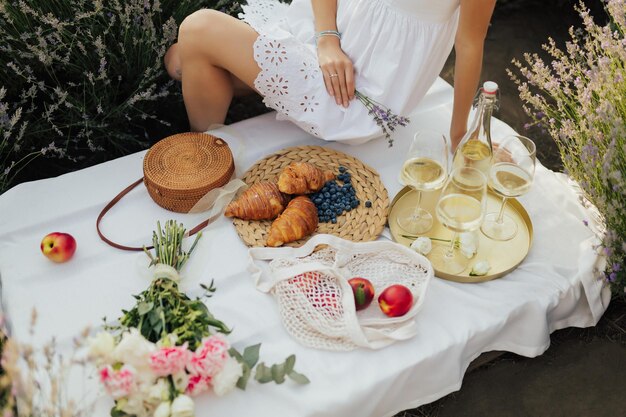 Une femme est assise sur une table avec une corbeille de fruits et de vin