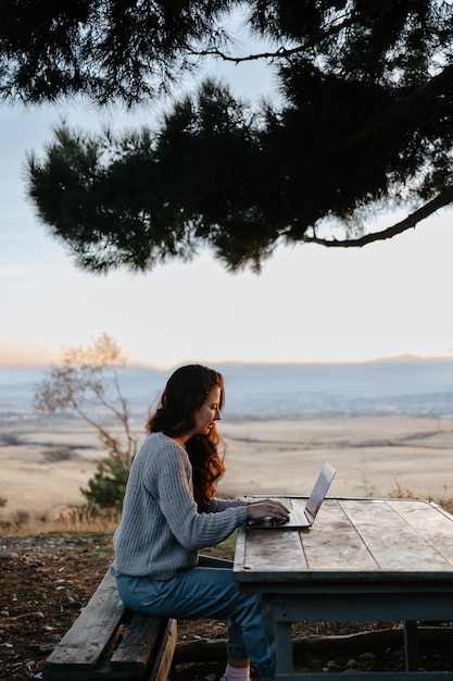 Une femme est assise à une table avec un ordinateur portable devant son travail à distance indépendant