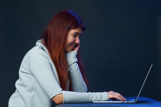 La femme est assise à table et utilise un ordinateur portable pour communiquer dans le chat ou le chat vidéo Concept de médias sociaux