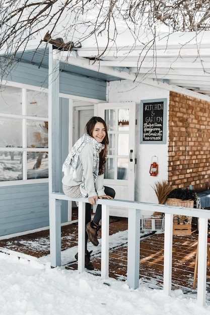 Une femme est assise sur la terrasse en hiver dans un tricot confortable.