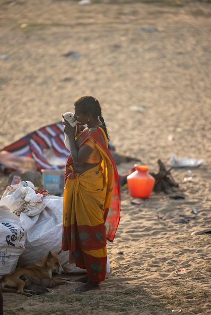 Une femme est debout sur la plage et boit de l'eau.