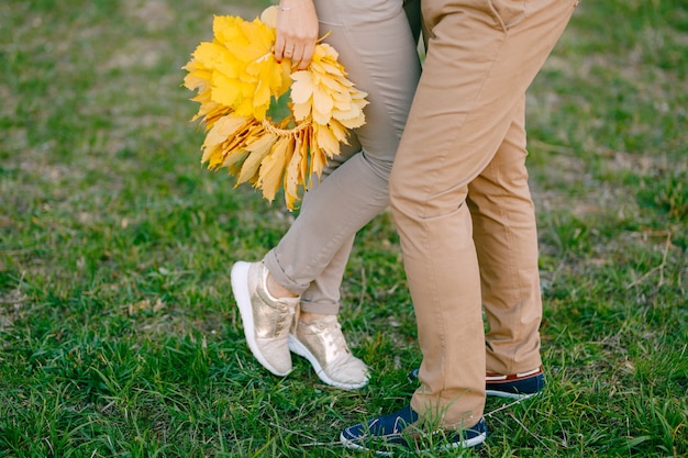 Femme est debout sur la pointe des pieds à côté de l'homme tenant une couronne de feuilles jaunes dans ses mains jambes bouchent