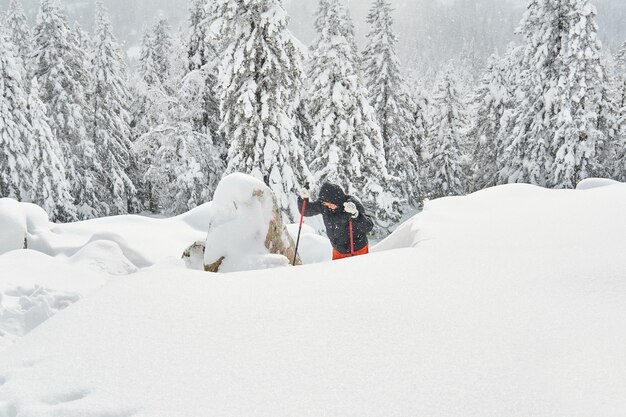 La femme est engagée dans le trekking dans les montagnes d'hiver pendant les chutes de neige