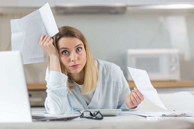 La femme est épuisée et frustrée par les documents du budget de l'entreprise ou de la famille à la maison