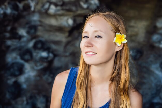 La femme est une touriste à Bali. Le rituel de l'ablution avec de l'eau bénite et sur son front prikleeli riz et mettre l'oreille fleur