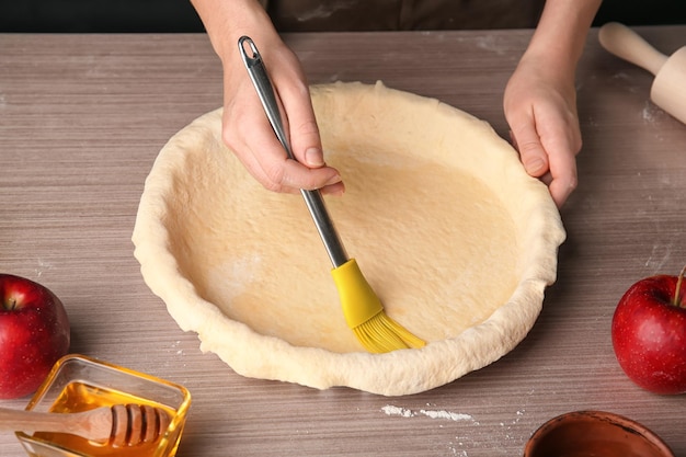 Femme étalant de l'huile sur une pâte feuilletée avec un pinceau