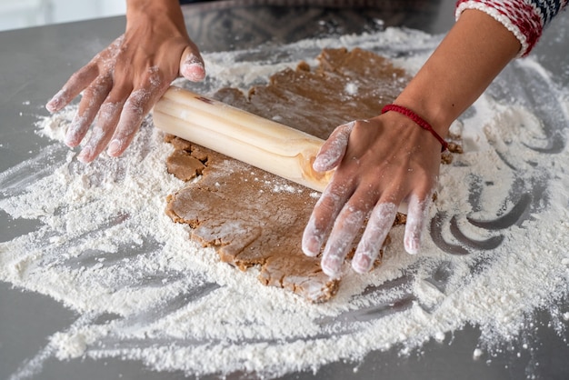 Femme étalant la pâte de pain d'épice avec rouleau à pâtisserie