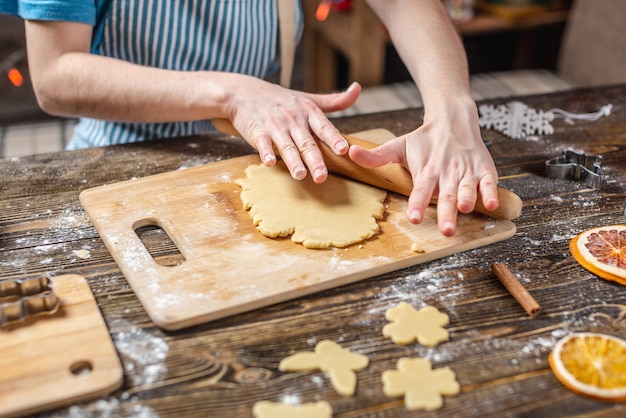 Femme étale la pâte avec un rouleau à pâtisserie et des formes