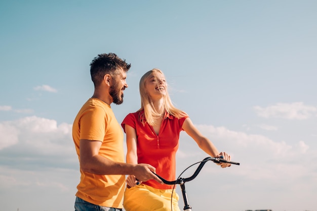 Femme d'été avec vélo rétro sur fond de ciel bleu Heureux couple d'amoureux Plus grandes histoires d'amour Couple en robe d'été fait du vélo Couple avec vélo vintage