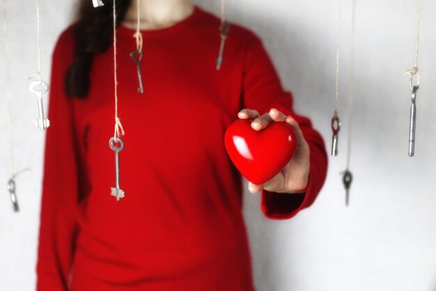 La femme étend sa main avec une forme de coeur rouge entouré d'un fil principal