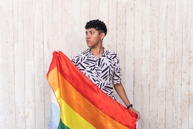 Femme ethnique contemplative avec drapeau LGBT à l'extérieur