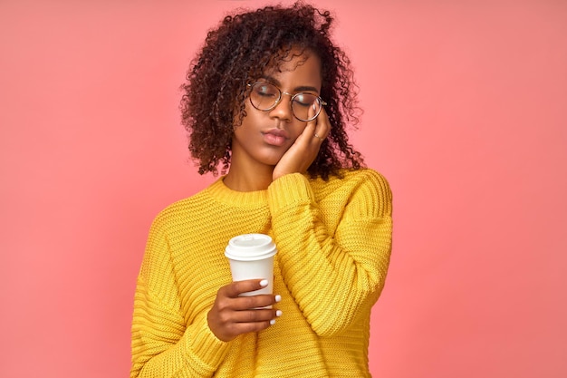 Une femme ethnique fatiguée et endormie couvre le visage avec une expression triste de paume ferme les yeux porte une tasse de boisson