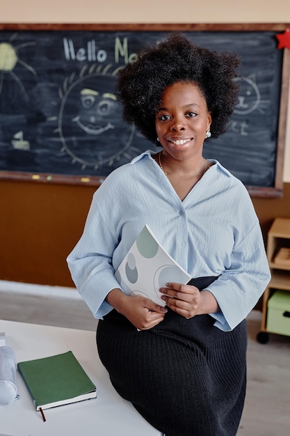 Une femme ethnique heureuse tenant un cahier à l'école
