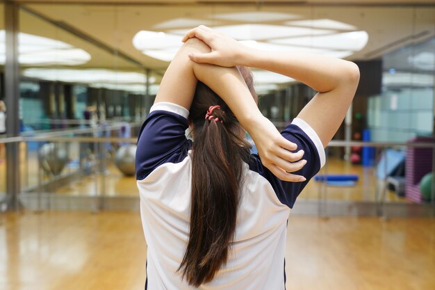 Une femme étire son épaule et son bras dans le fitness