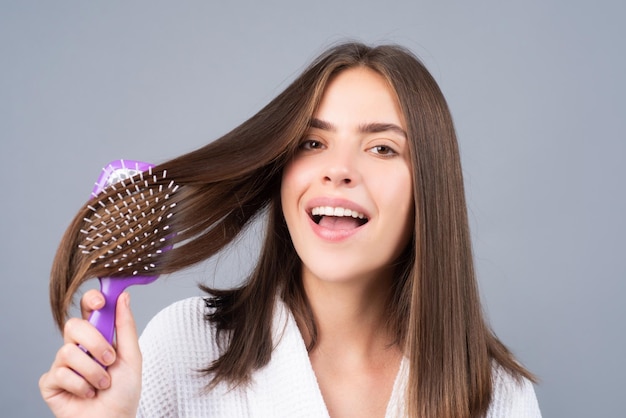 Femme étonnée se peignant les cheveux Portrait en gros plan d'un modèle féminin avec un peigne se brosser les cheveux Fille avec une brosse à cheveux soins et beauté des cheveux