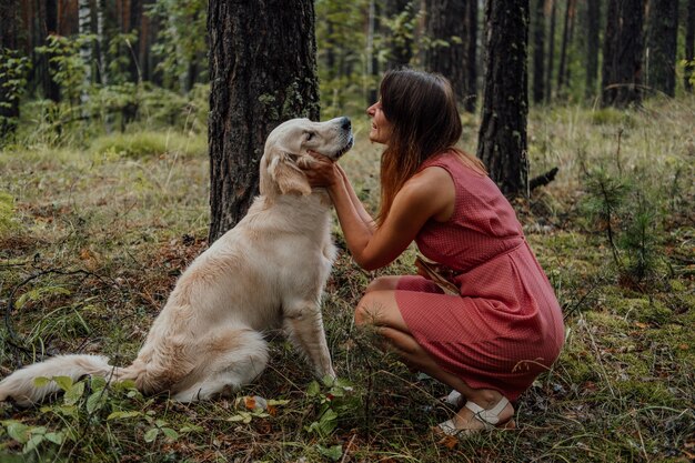 Femme étreignant le golden retriever dans la forêt