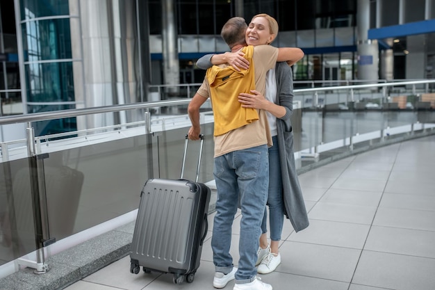 Femme étreignant un homme avec une valise dans le terminal