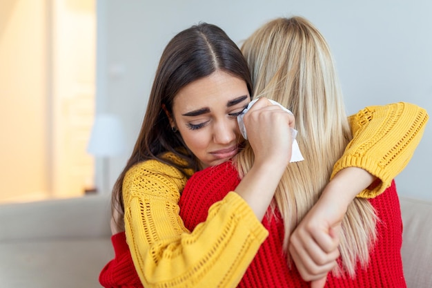 Femme étreignant son amie déprimée à la maison, en gros plan. Jeune femme soutenant sa petite amie qui pleure. Amitié réconfortante et attentionnée, espace copie