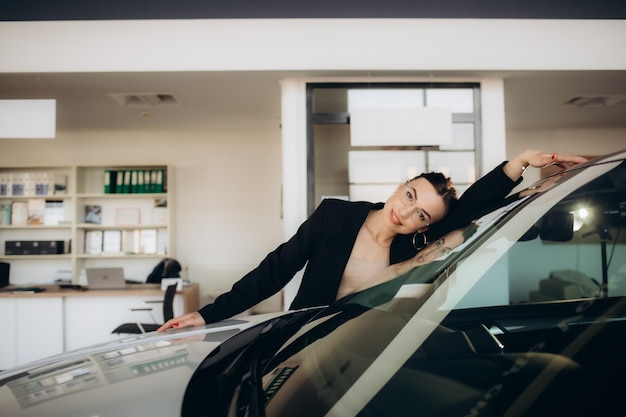 Une femme étreint une voiture dans une salle d'exposition.