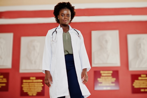 Femme étudiante afro-américaine en blouse de laboratoire avec stéthoscope à l'intérieur de l'université médicale.