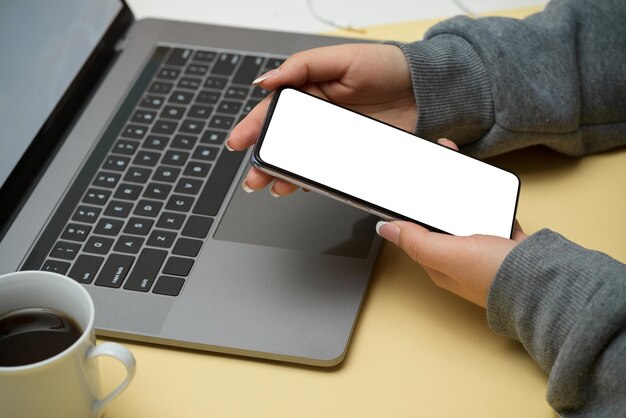 Femme ou étudiante à l'aide d'un smartphone sur sa maquette d'écran vide de téléphone de bureau