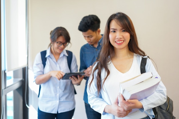 femme étudiante asiatique souriant et porter des manuels avec un groupe d&#39;amis à l&#39;université intérieure