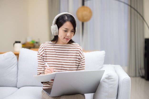 Femme étudie sur un ordinateur portable et note des notes à la maison