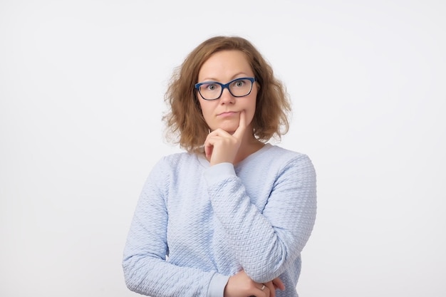 Femme européenne d'âge moyen dans des verres bleus pensant et regardant la caméra confuse à propos d'une idée