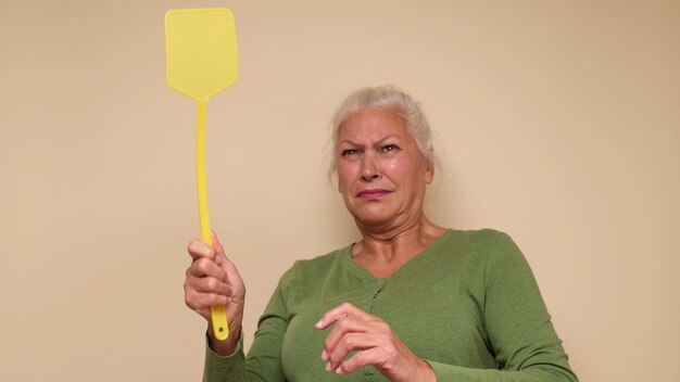 Photo une femme européenne âgée essaie d'attraper un moustique avec une tapette à mouches