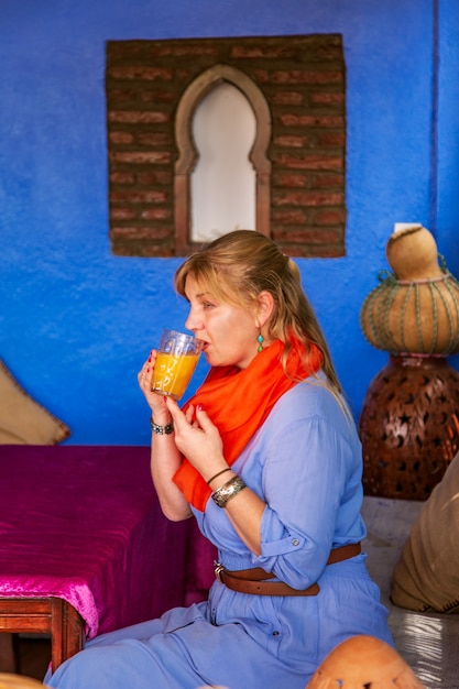 Femme européenne boit du jus dans un café marocain. Intérieur oriental authentique. Chefchaouen, Maroc