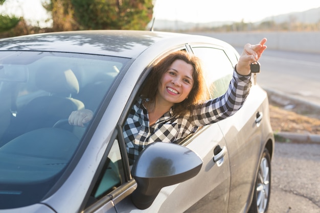 Femme européenne derrière la roue de voiture montrant la clé de voiture