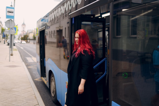 Une femme européenne de grande taille sort du bus jeune fille positive aux cheveux roses rouges