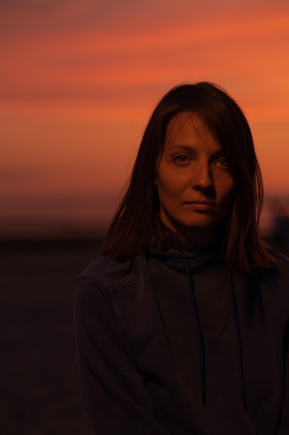 Photo une femme européenne illuminée par la lumière du néon dans un chapeau sur le fond du ciel au coucher du soleil