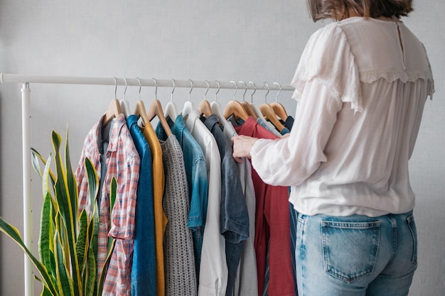 Une femme européenne à la maison dans une armoire sélectionne des vêtements pour une fête ou une fête d'anniversaire triant les vêtements